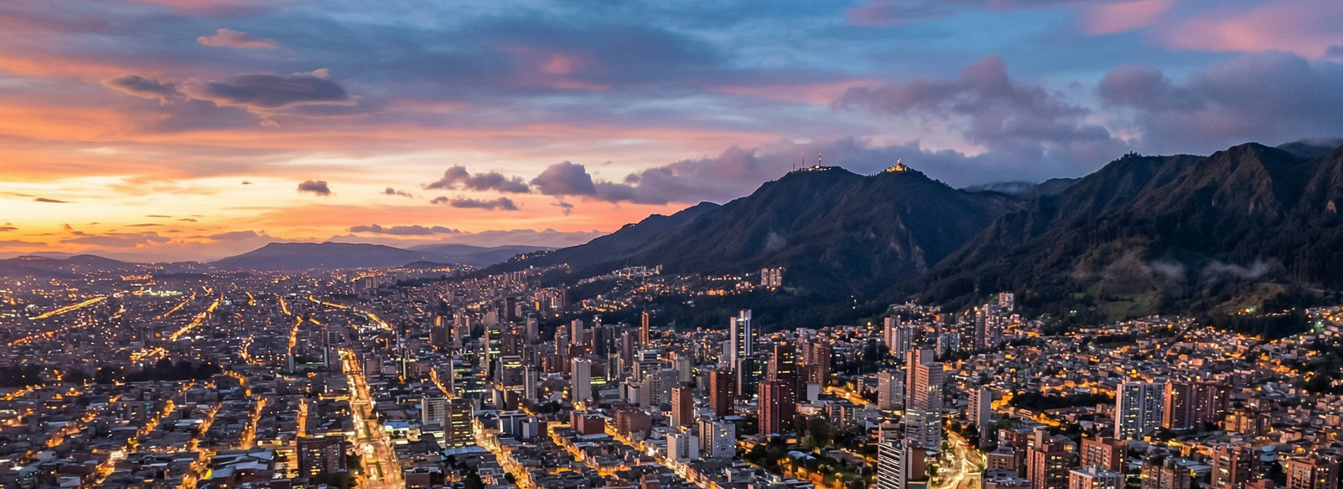 Vista aérea de Bogotá al amanecer con horizonte urbano y luz dorada